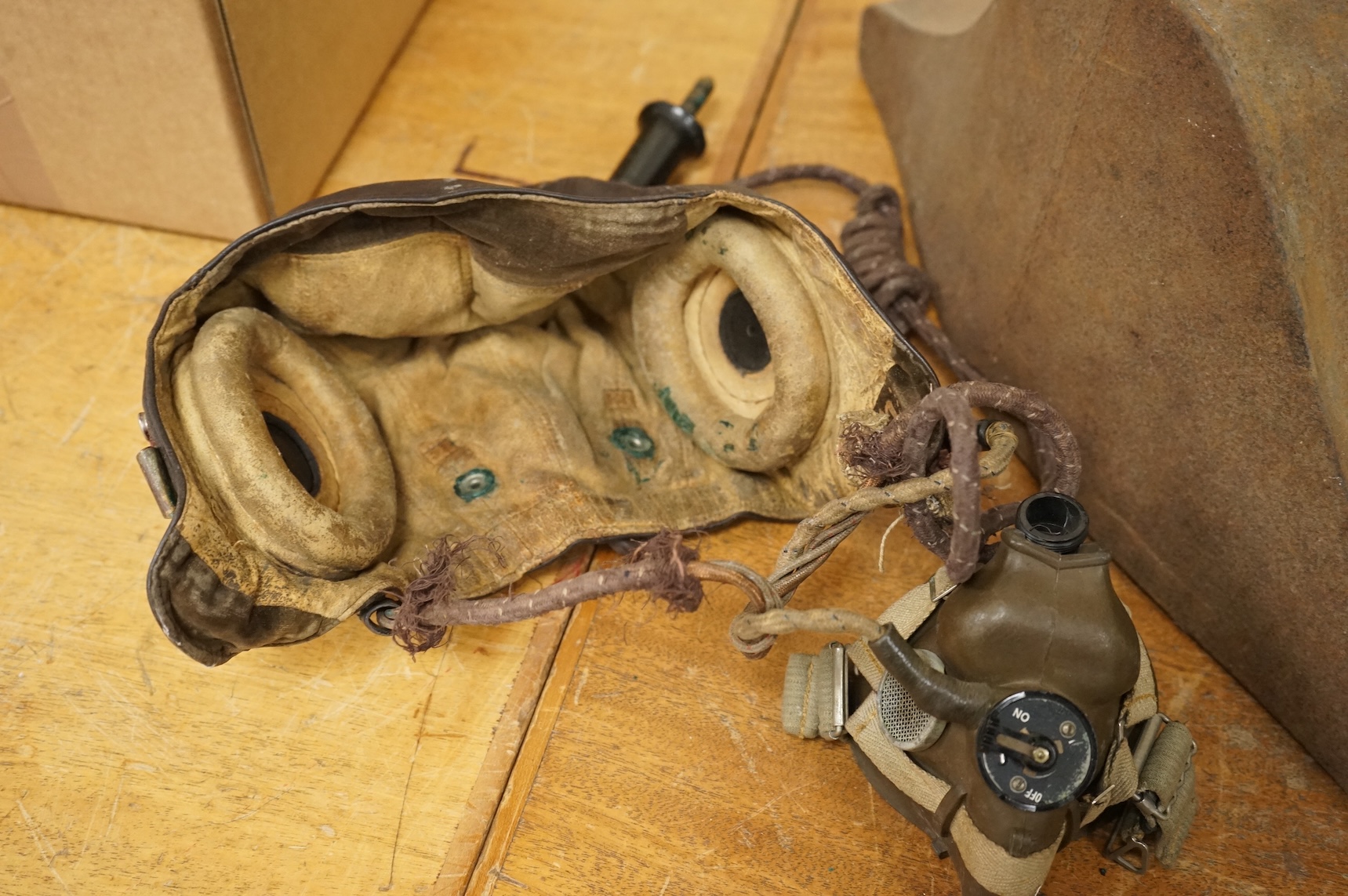 A WWII RAF Air Ministry aviator’s leather head-gear, with built-in padded headphones, oxygen mask with microphone and other electrics incorporated into it, marked with a crown and ‘AM 10A/13466’ to one earpiece, together